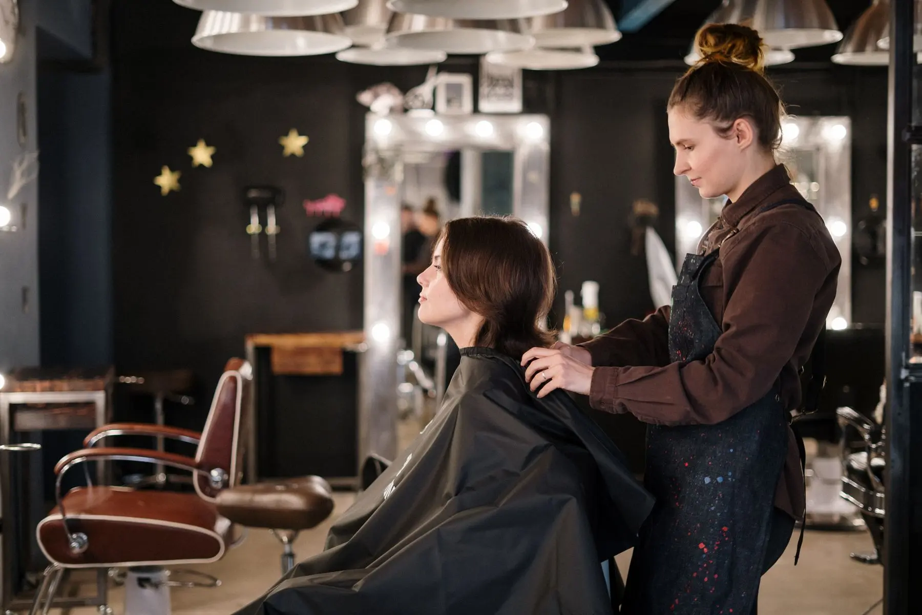 Stylist checking the shape of a client's finished haircut in a modern salon